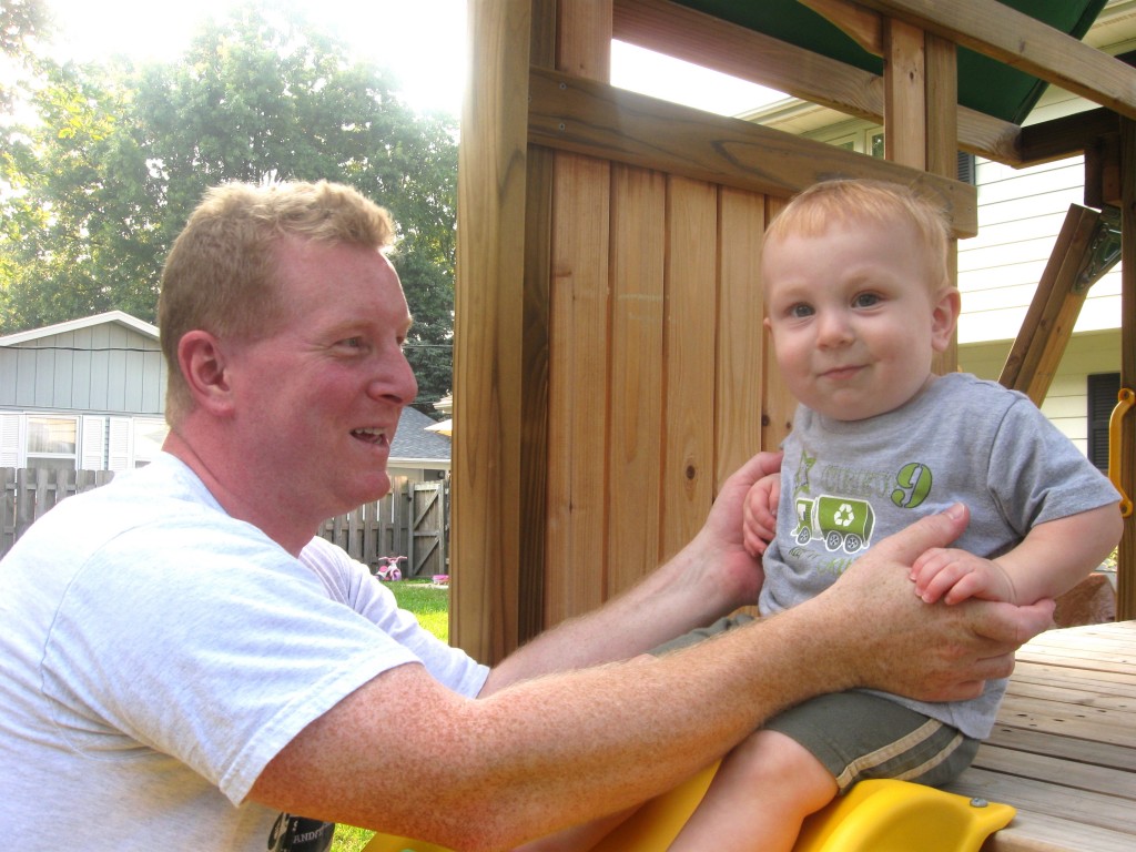 Daddy helping Andrew go down the slide.