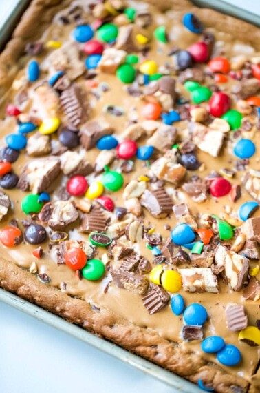 Skip all the hassle of measuring, mixing and scooping cookie dough and create this Chocolate Chip Candy Cookie Bar.  With all the fun flavors of a chocolate chip cookie with loads of candy bar toppings and peanut butter, make these Chocolate Chip Cookie Bars exceptionally special! #chocolatechipcookiebars #chocolatechipcookies #chocolate #cookies #peanutbutter | allthingsmamma.com
