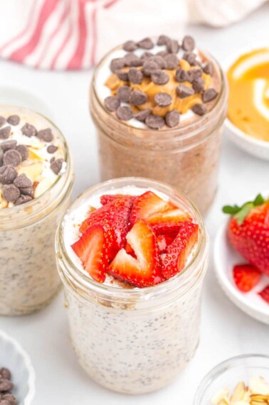 overnight oats with chia seeds in mason jar with spoon, topped with sliced strawberries.