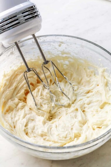 Bowl of cream cheese frosting with hand mixer.