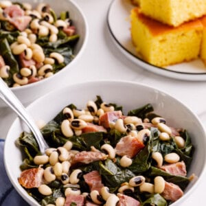 Bowls of collard greens next to a plate of cornbread.