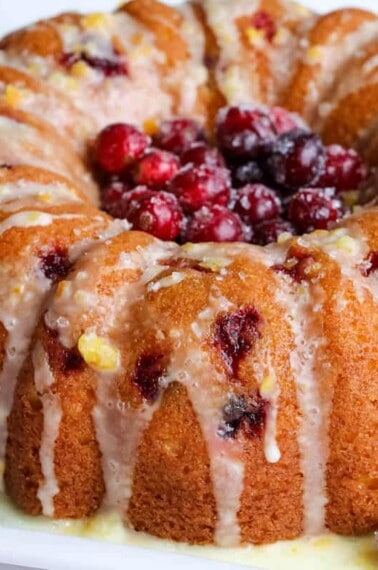 bundt cake topped with sugared cranberries and orange glaze