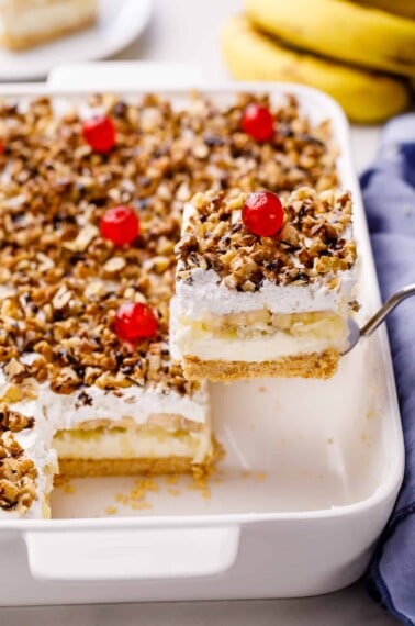 A slice of banana split cake being lifted from a pan.