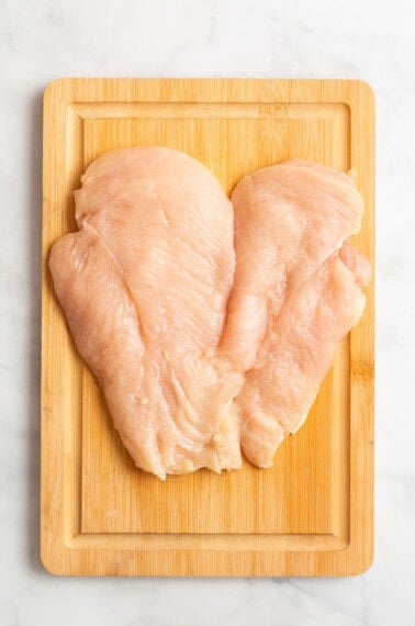 Butterflied chicken breast on a cutting board.