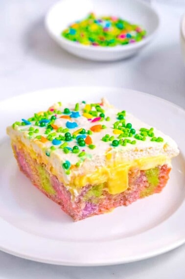 A slice of Easter poke cake topped with sprinkles on a plate.