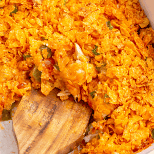 A wooden spoon scooping into Dorito chicken casserole.