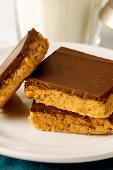 Three no-bake peanut butter bars on a plate.