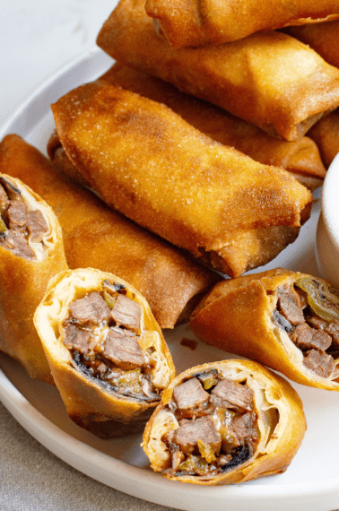 Philly cheesesteak egg rolls on a plate.