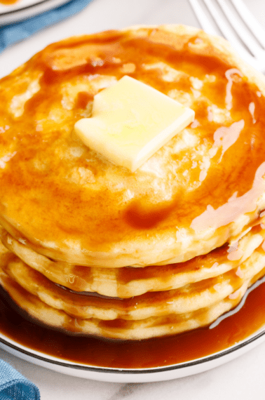 A stack of overnight pancakes topped with butter and syrup.