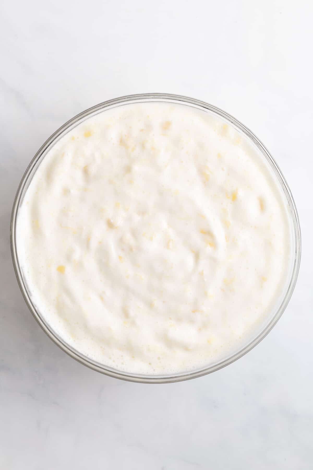 pineapple angel food cake batter sitting in a large glass bowl