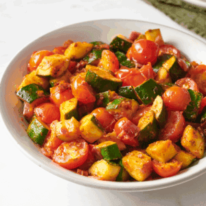 A bowl of sautรฉed zucchini and tomatoes.