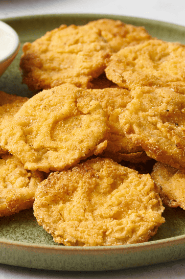 A plate of fried green tomatoes with a bowl of dipping sauce.