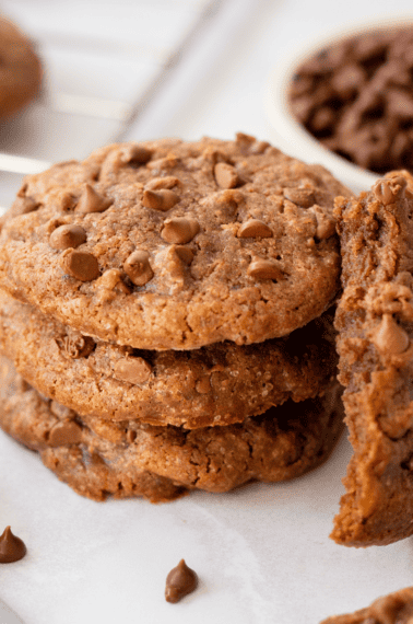 A stack of coffee cookies with one missing a bite laid against it.