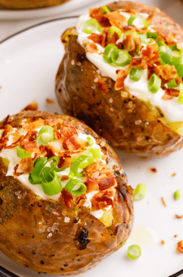 Two loaded baked potatoes on a plate.