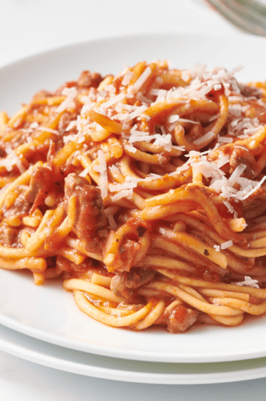 Crock pot spaghetti on a plate topped with Parmesan cheese.