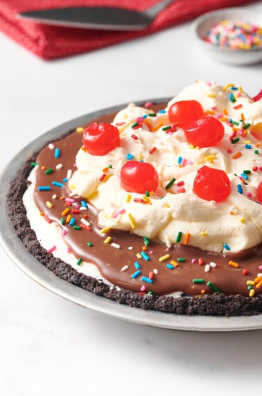 An Oreo crust ice cream pie topped with whipped cream and cherries.