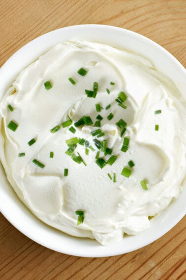 A bowl of homemade sour cream topped with chives.