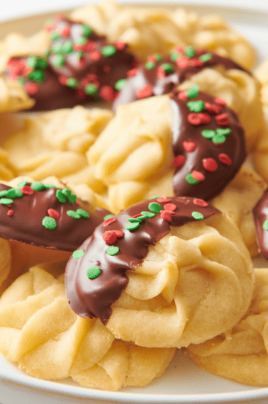 A plate of Christmas butter cookies, some with chocolate and sprinkles.