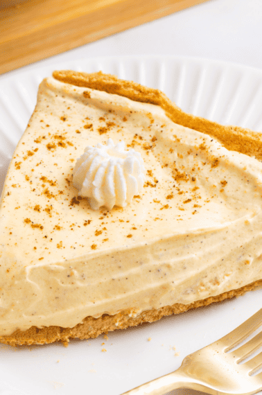 A slice of no bake egg nog pie topped with whipped cream on a plate.