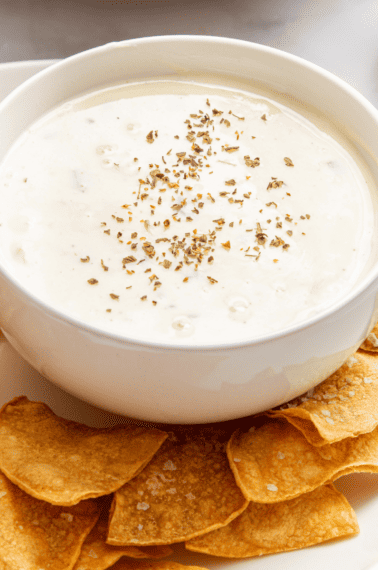 A bowl of Velveeta queso blanco recipe surrounded by tortilla chips.