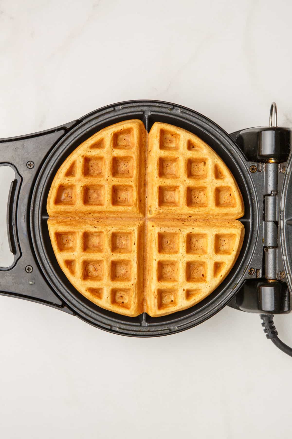 How to Make Waffles with Pancake Mix A waffle being cooked in a waffle iron.