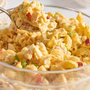 A spoon lifting a scoop of deviled egg pasta salad from a bowl.