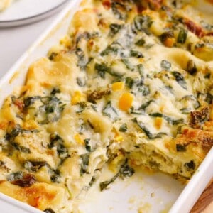 A dish of vegetable lasagna with a square missing.