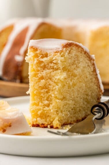 A slice of glazed 7UP Pound Cake on a plate with a fork.
