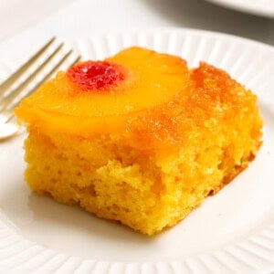slice of pineapple upside down cake on a white plate.