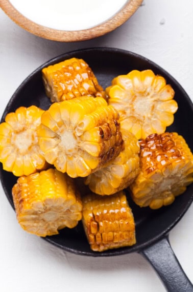 Grilled corn on the cob in a pan, cut into smaller pieces.