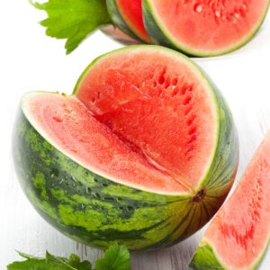 A whole watermelon with a large wedge missing.
