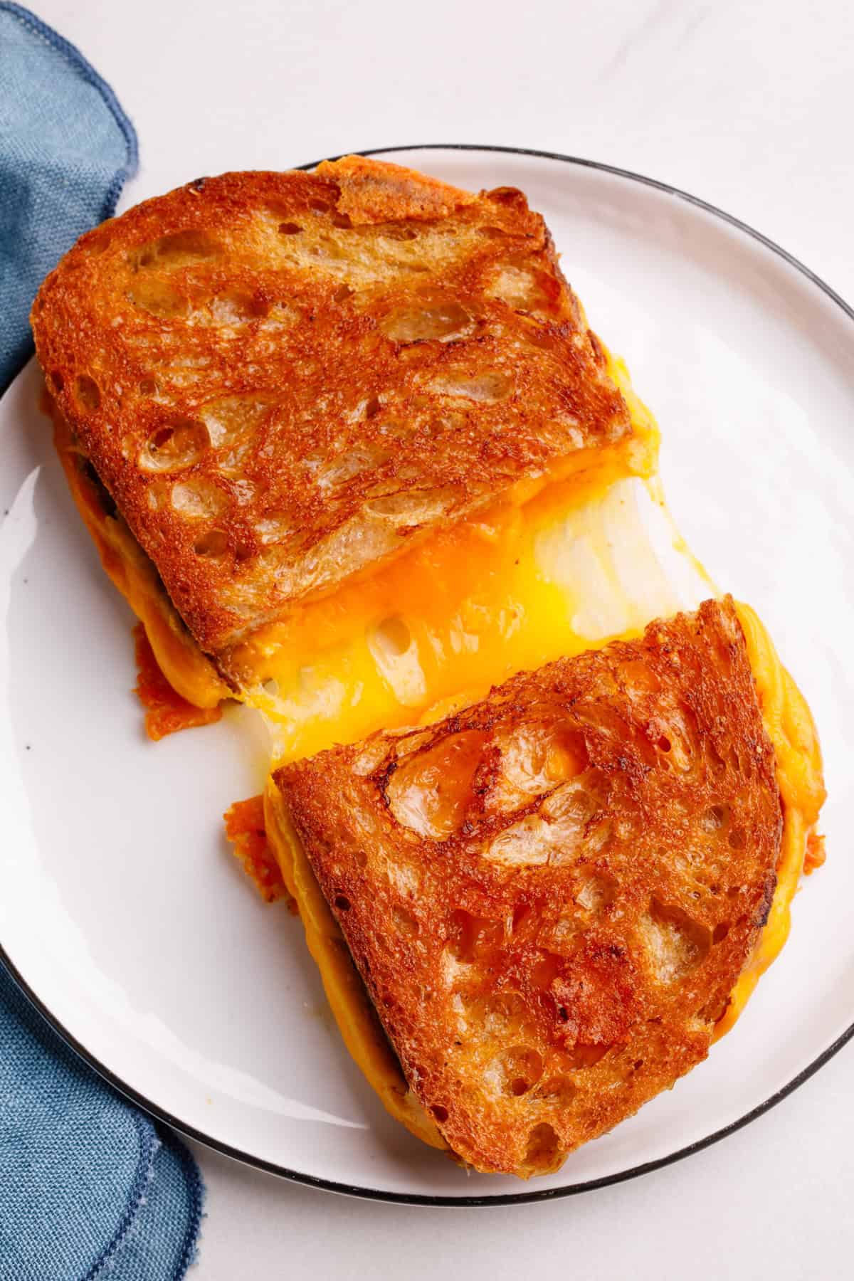 Grilled Cheese Sandwich A grilled cheese sandwich cut in half with the melty cheese coming out on the plate.