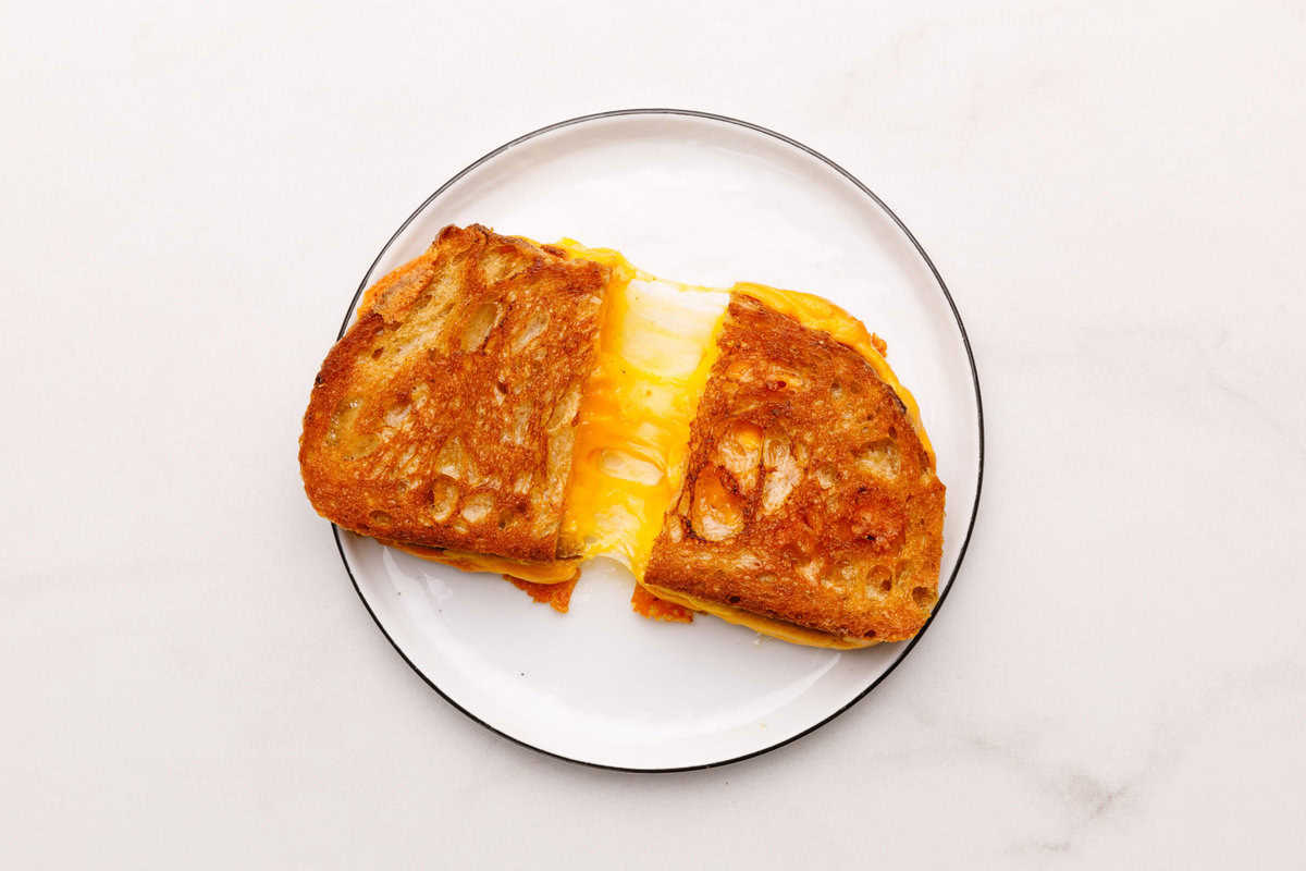 Grilled Cheese Sandwich A sliced Grilled Cheese Sandwich sitting on a white plate.
