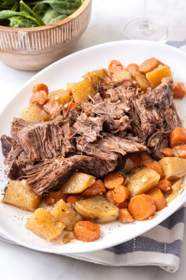 pot roast with vegetables on a white plate.