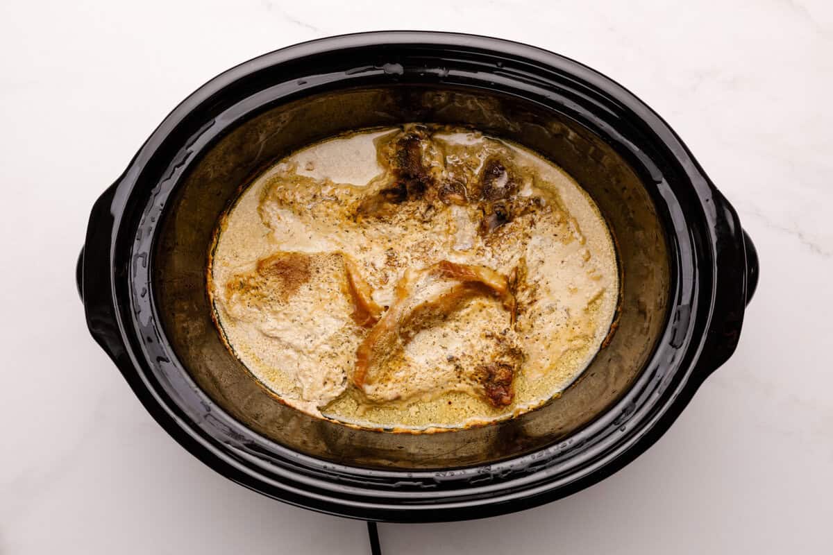 Crockpot pork chops in slow cooker bowl Cooked pork chops in a crockpot.
