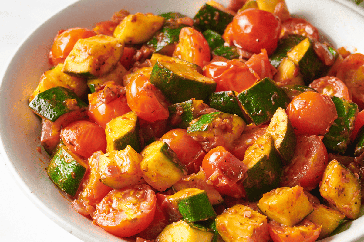 A bowl of sautรฉed zucchini and tomatoes.