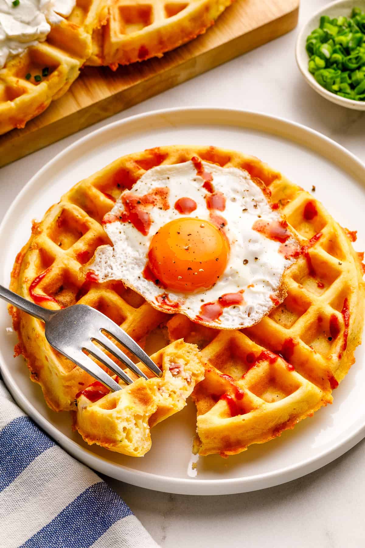 a savory waffle on a white plate being cut