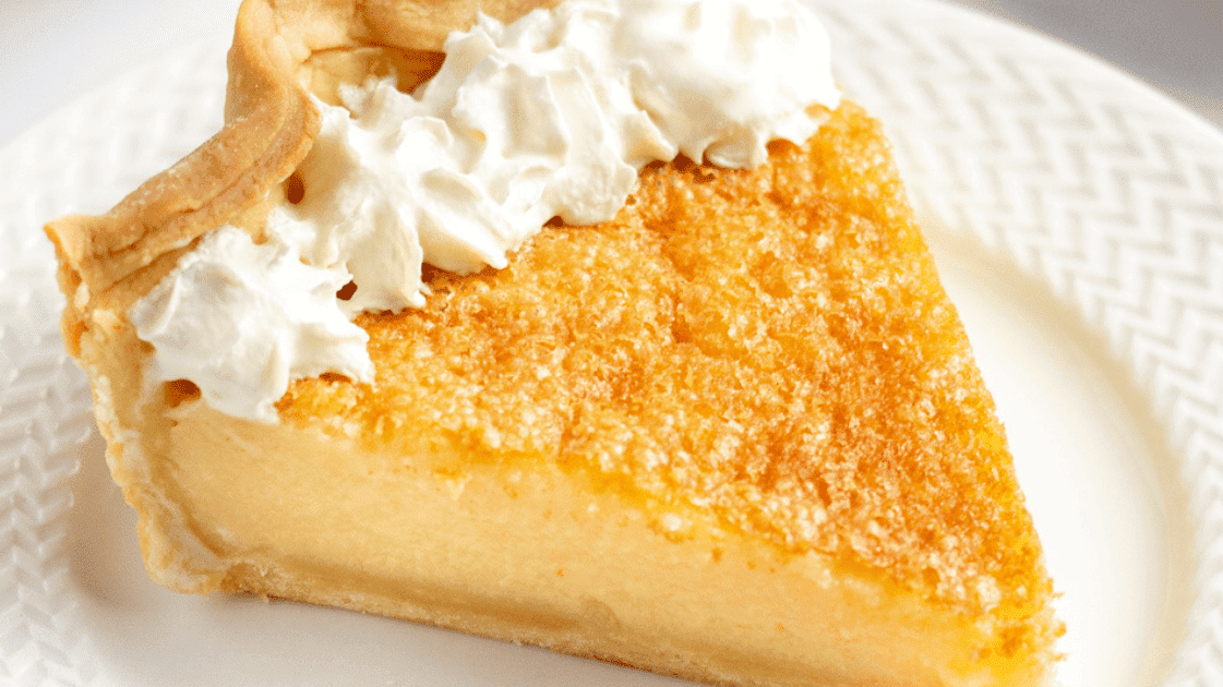 slice of buttermilk pie with whipped cream served on a white plate