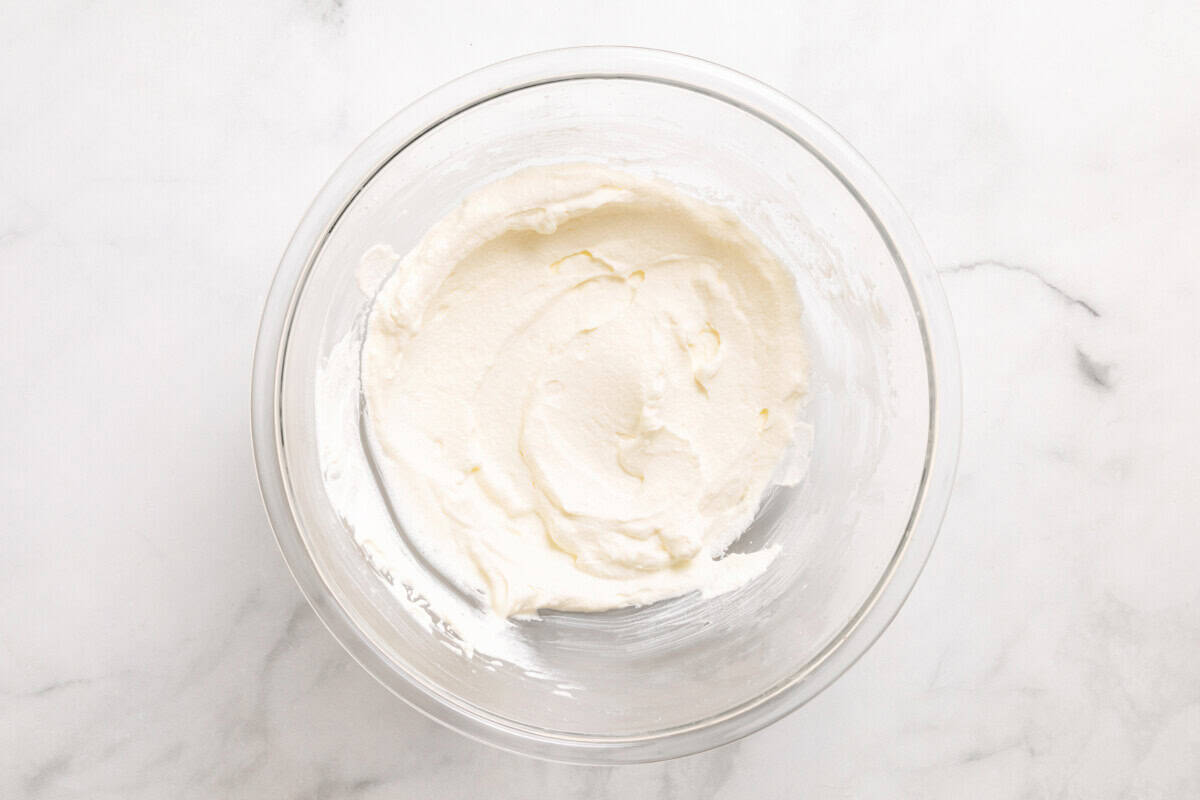 Overhead view of whipped cream in glass mixing bowl