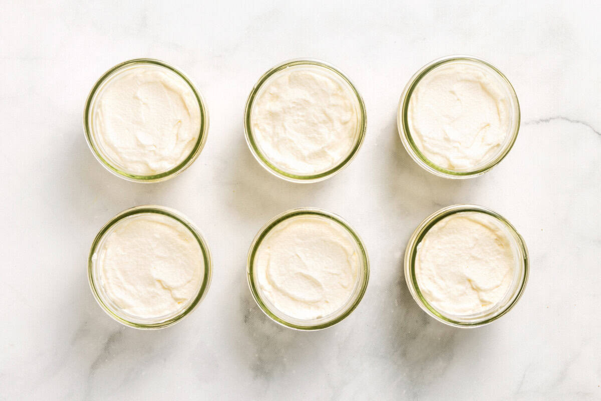 Overhead view of coconut cream pie parfaits in jars with whipped cream on top